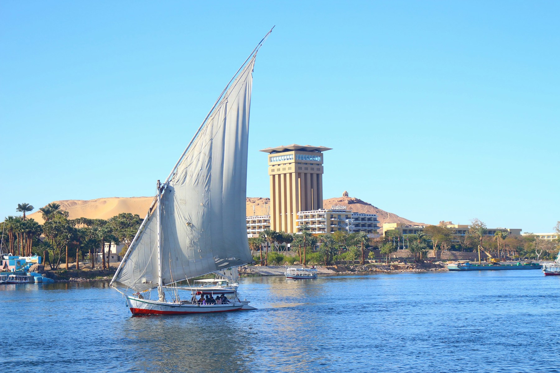 Traditional white-sailed felucca crossing the Nile